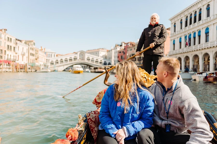 Couple in a gondola on the Grand Canal looking back at the Rialto Bridge