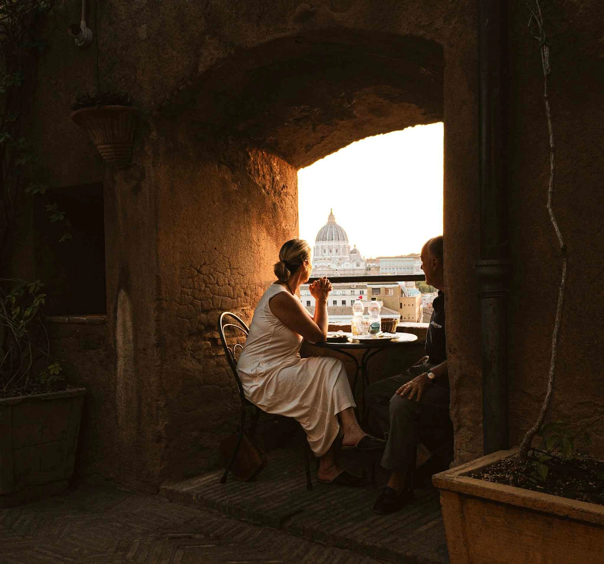 Two tourists look at St. Peter's Basilica from a rooftop in Rome