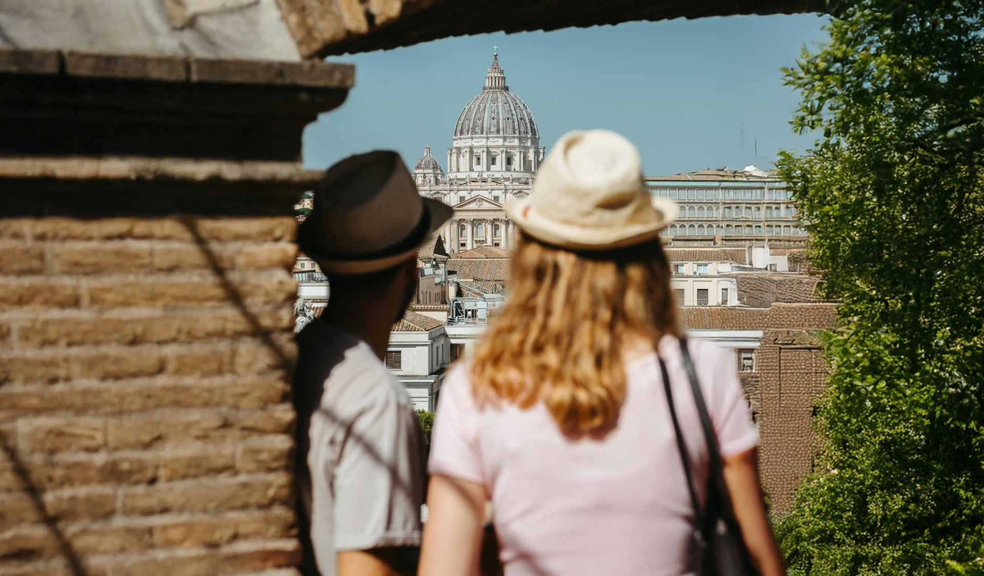 Two tourists look at St. Peter's Basilica from a rooftop in Rome