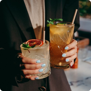 Close up of person holding two cocktails