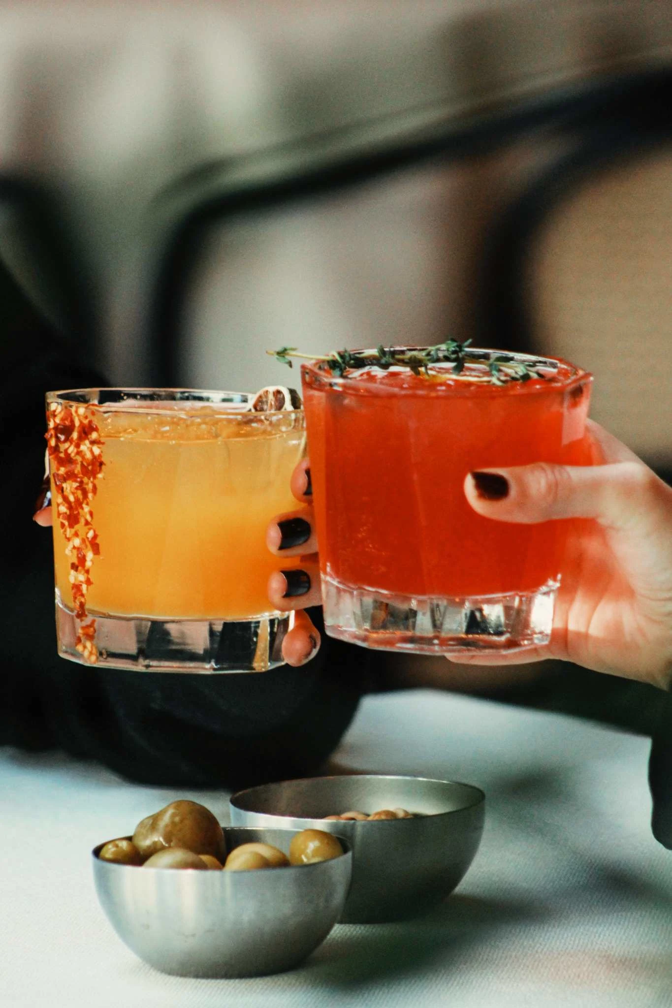 Close up of person holding two cocktails