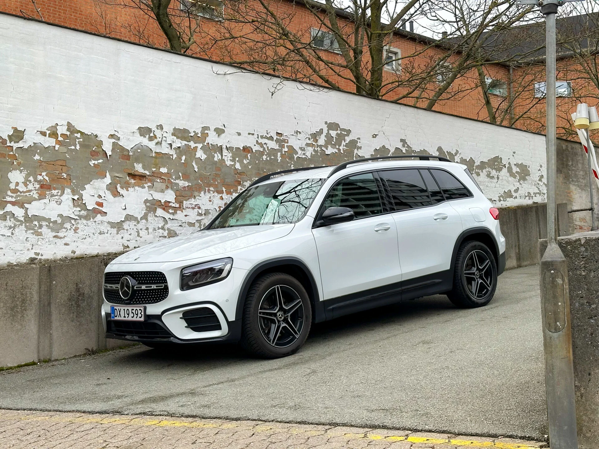 Vit Mercedes-Benz GLB parkerad i backe vid vit betongvägg
