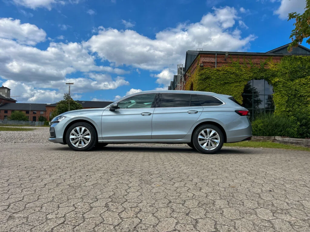 Grå Skoda Superb Combii på stenlagd yta med hus i bakgrunden