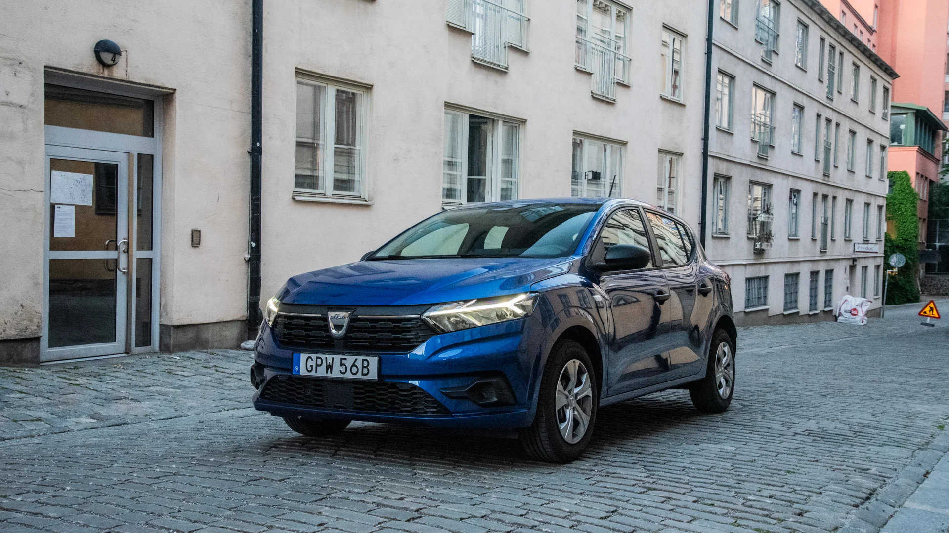 Blå Dacia Sandero fotad framifrån på stenig stadsgata