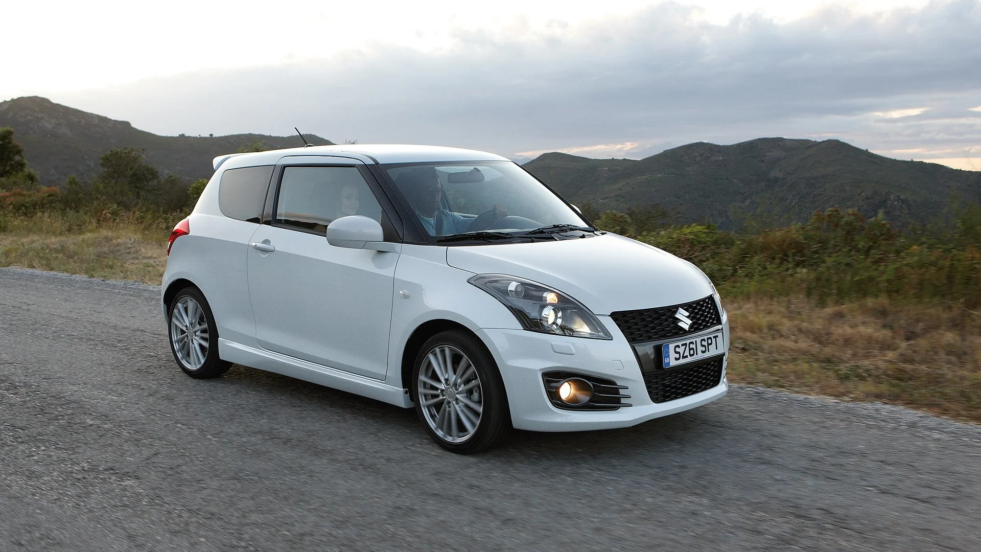 Vit Suzuki Swift på landsväg bland berg