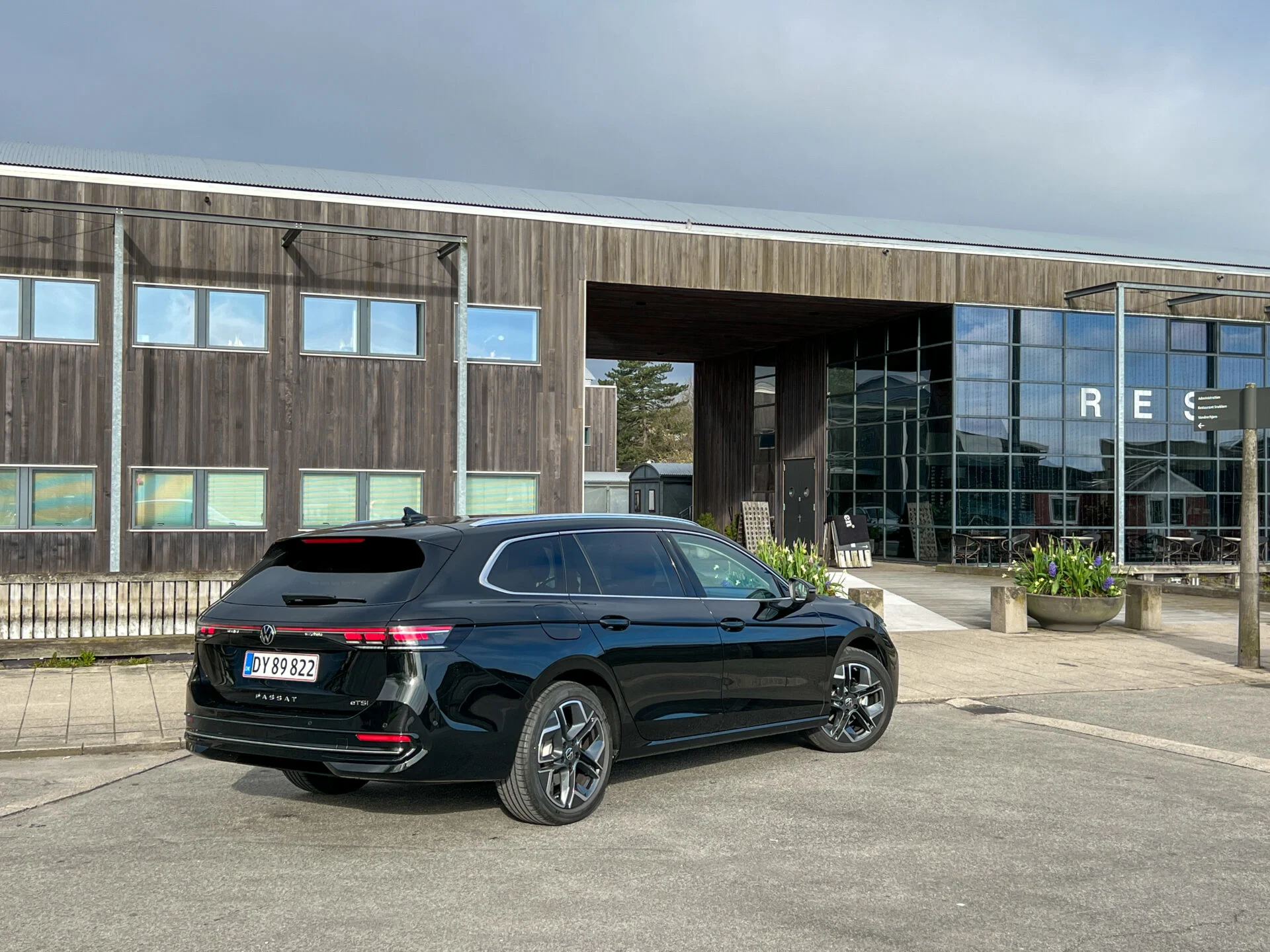 Mörk Volkswagen Passat parkerad utanför träbyggnad