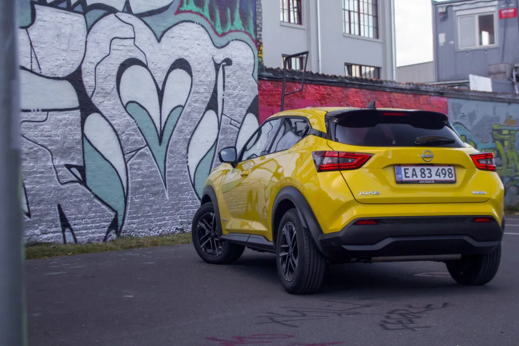 Baksidan av gul Nissan Juke parkerad framför graffitimålad vägg