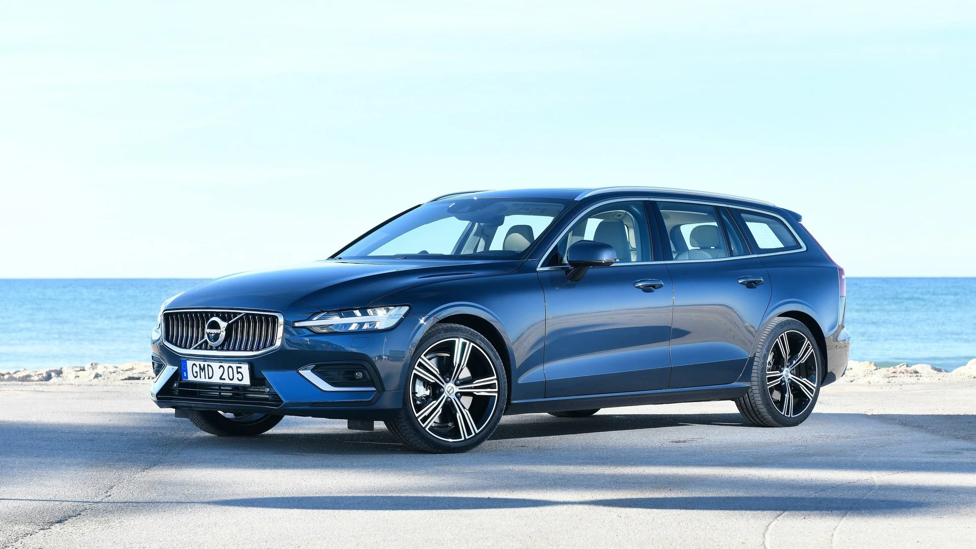 Blå Volvo V60 parkerad med havet i bakgrunden.