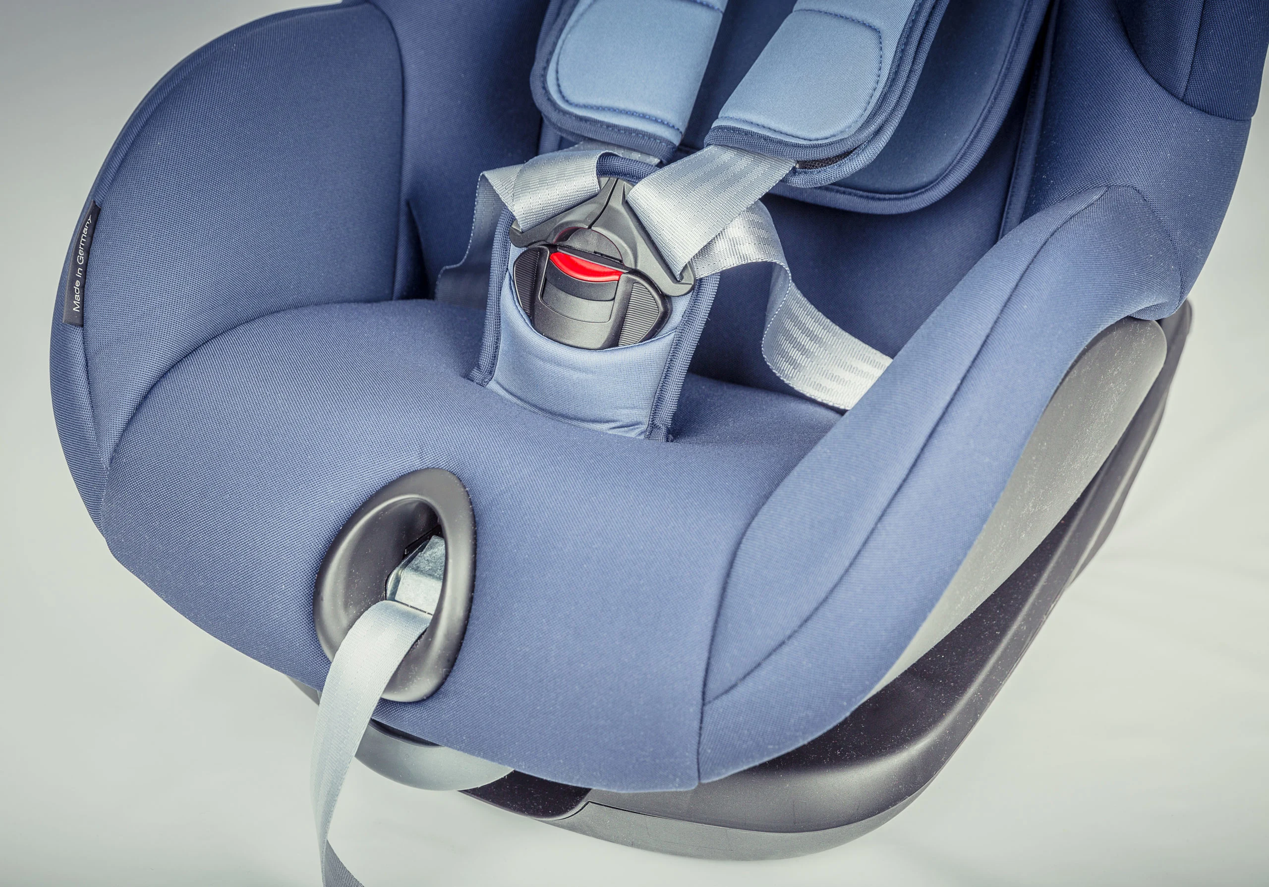 Närbild av en blå bilbarnstol med säkerhetsbälte och spänne.