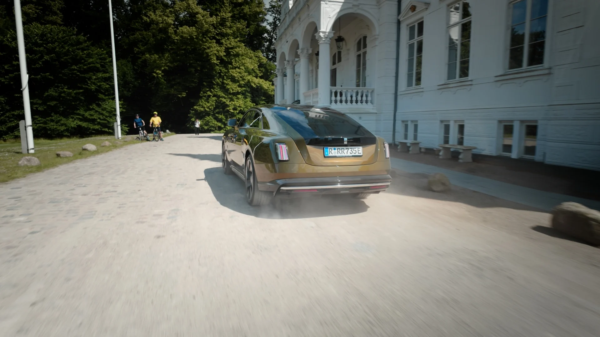 Guldig rolls royce sedd bakifrån utanför vit byggnad