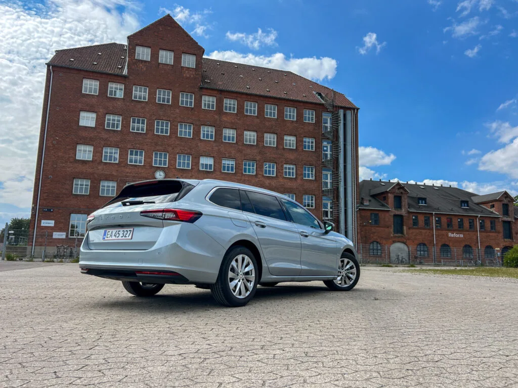 Grå Skoda Superb Combi på stenlagd yta med hus i bakgrunden