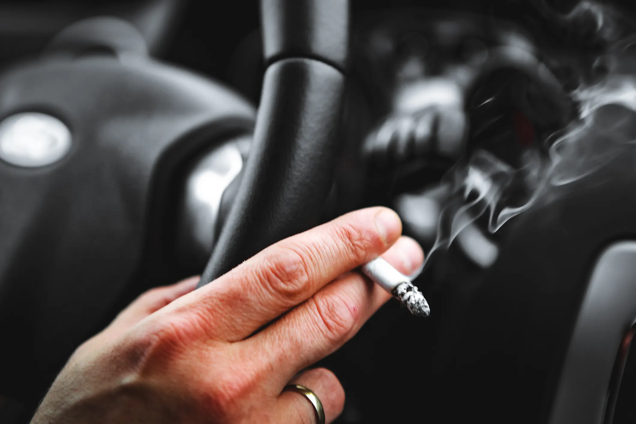 Närbild på hand som håller i cigarett i bil