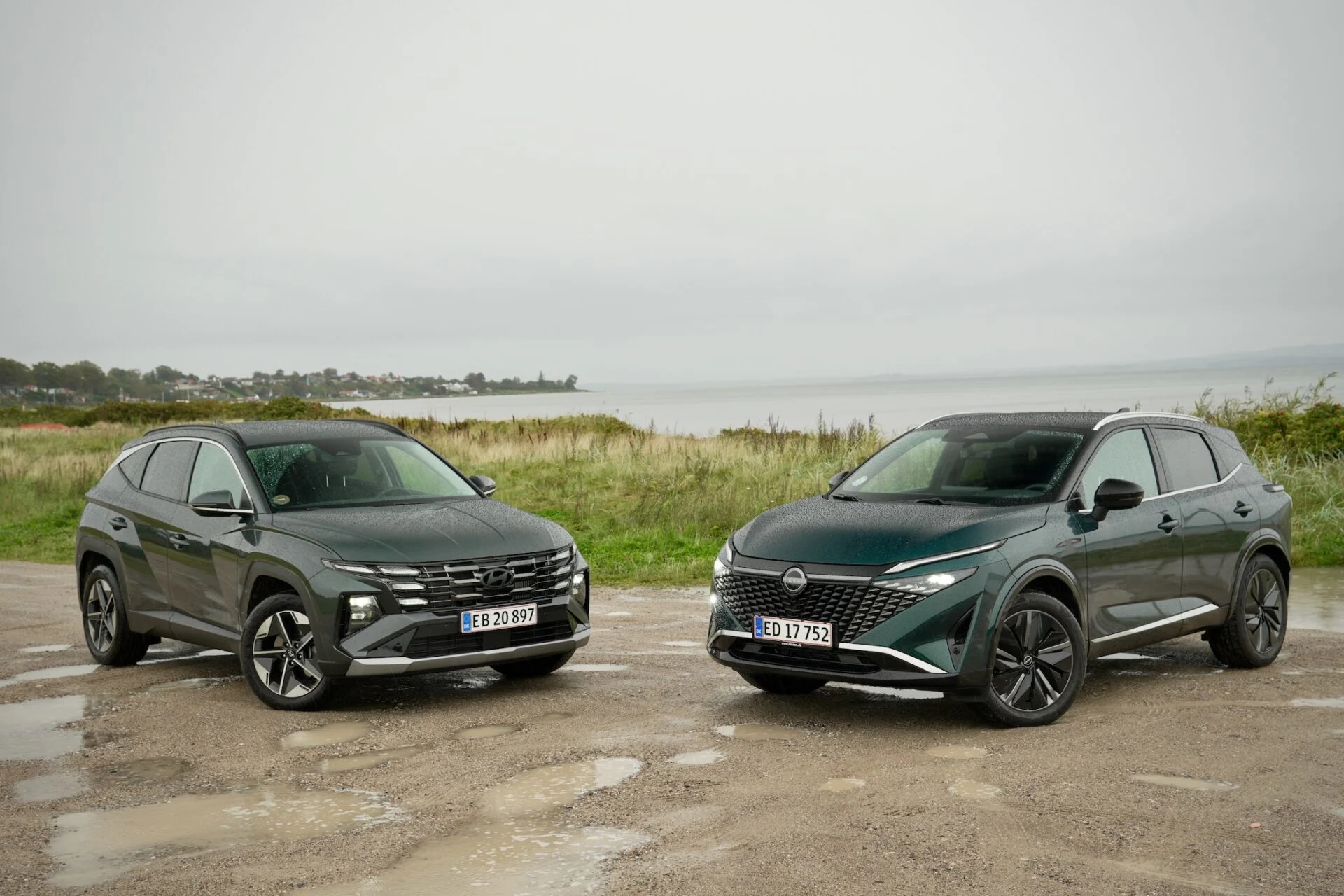 Mörk Nissan Qashqai och mörk Hyundai Tucson parkerade vid vatten
