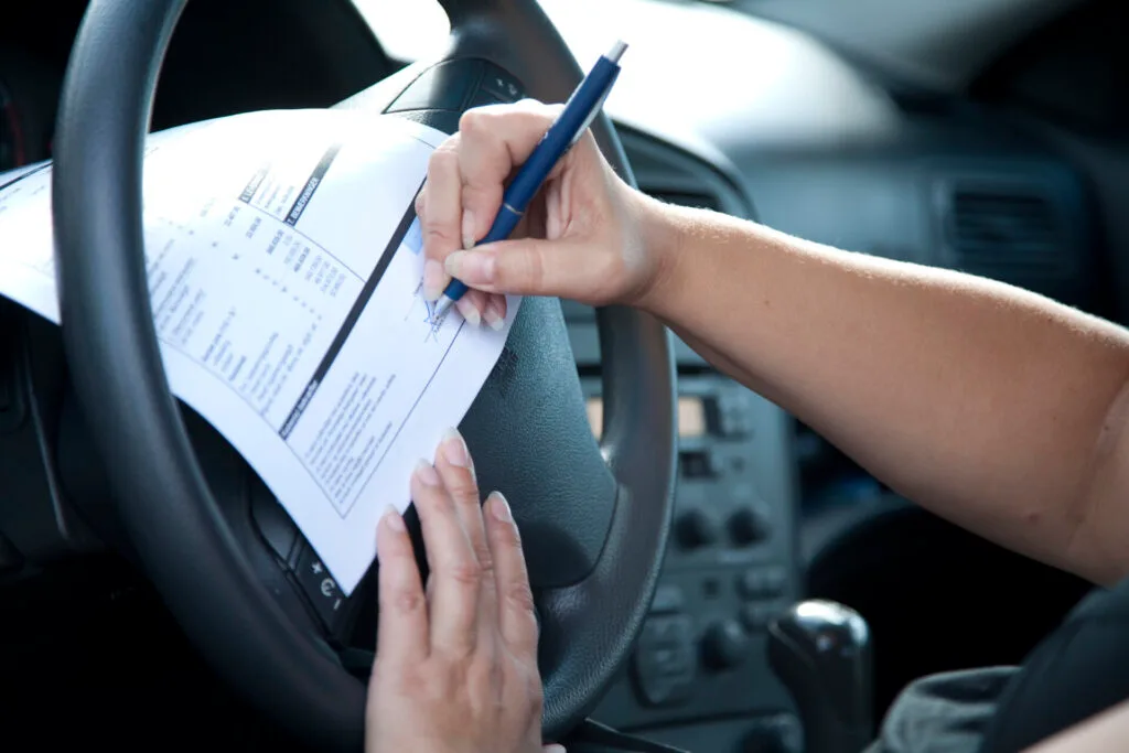 Närbild på händer som skriver under papper i bil