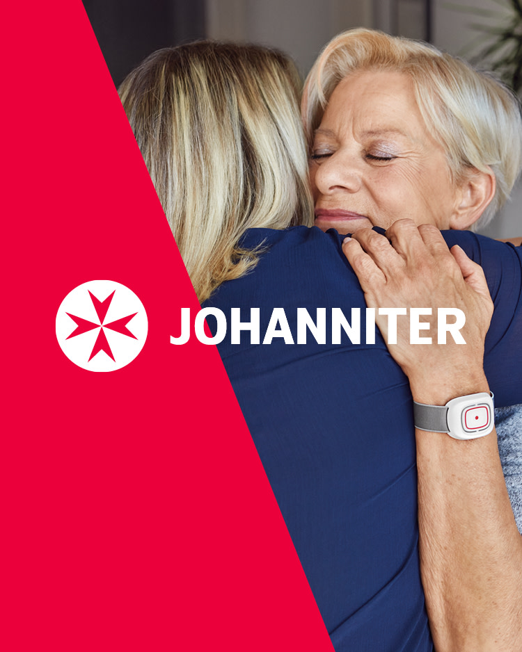 Zwei Frauen umarmen sich und das Logo von Johanniter ist zu sehen.