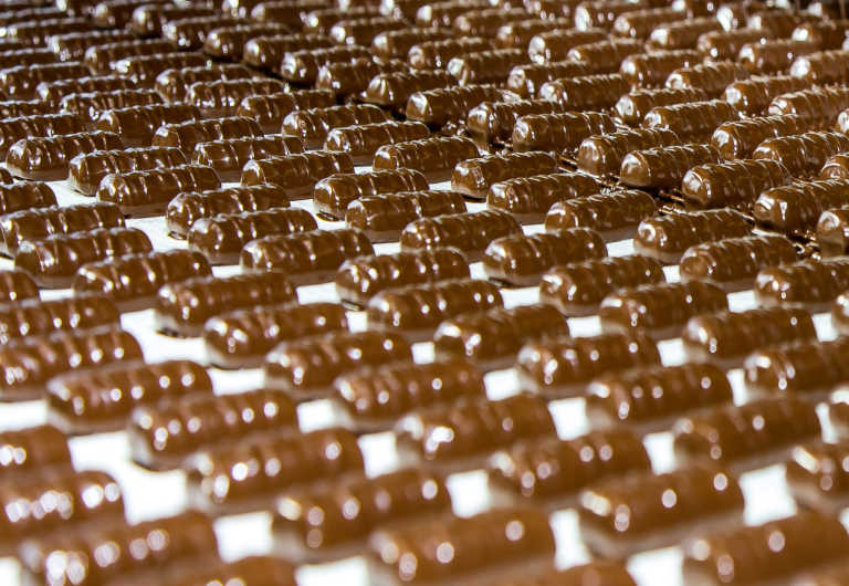 Hundreds of chocolate-covered bars cooling on a conveyor belt