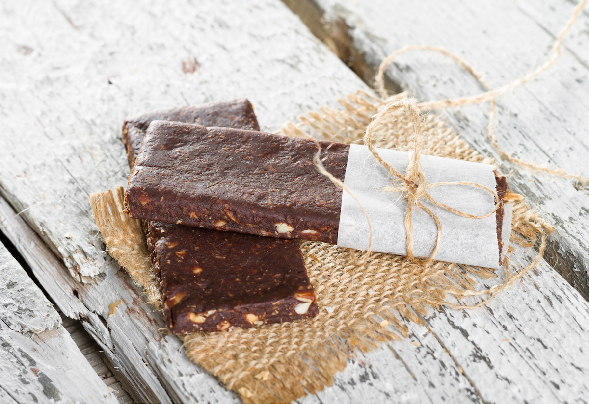 Two nutritional bars wrapped with twine, sitting on a wooden backdrop