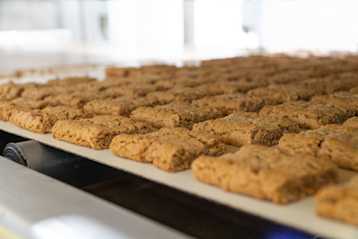 Brown crunchy bars sitting on a conveyor belt