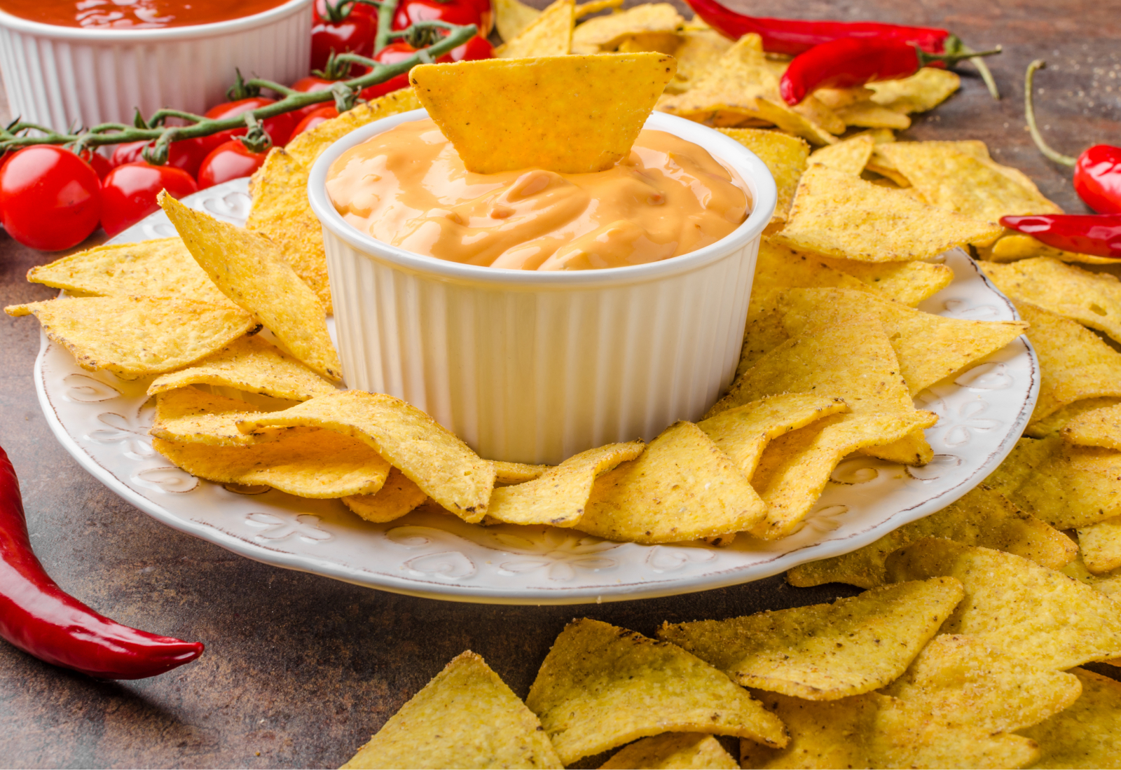 A plate of golden chips surround a single bowl of cheese dip
