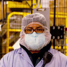 A masked Hearthside worker standing in front of yellow equipment