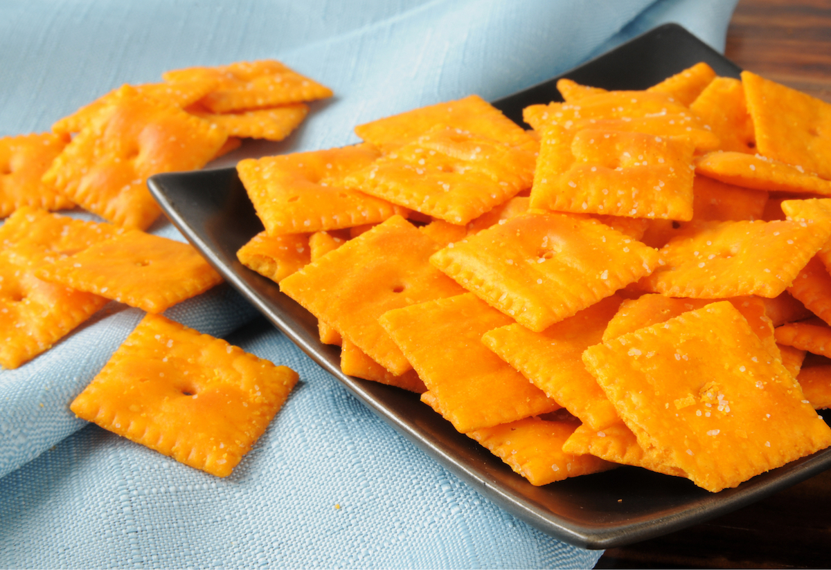 Cheese crackers on a black plate, with a light-blue fabric backdrop
