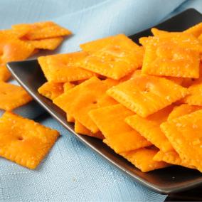 Cheese crackers on a black plate, with a light-blue fabric backdrop