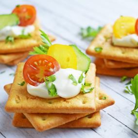 Stacks of savory crackers with tomatoes and sour cream on top.