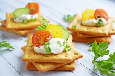 Stacks of savory crackers with tomatoes and sour cream on top.