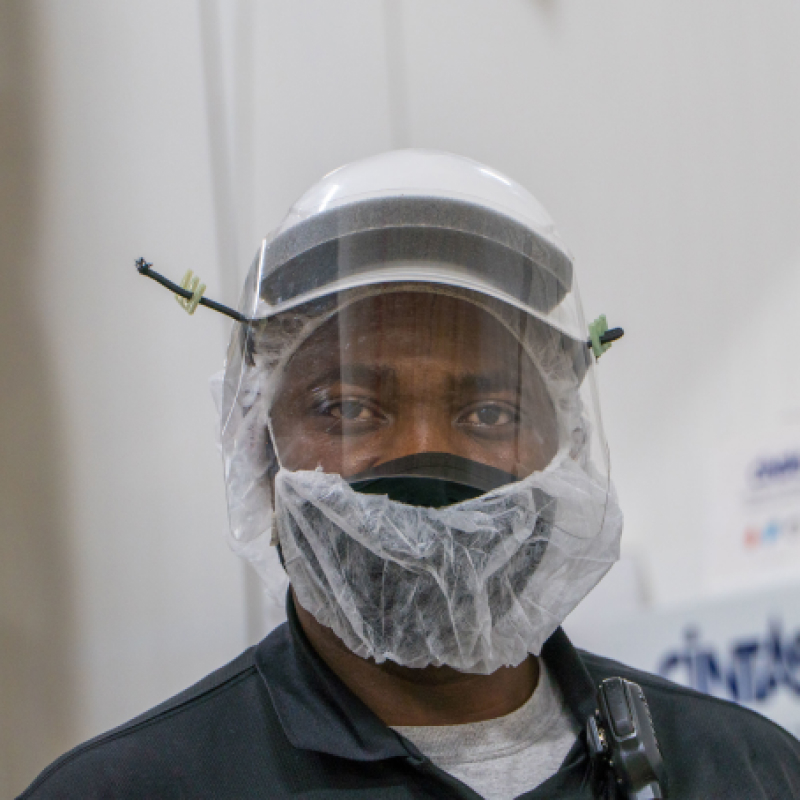 A masked Hearthside worker wearing a face mask, mesh mask, and clear face shield