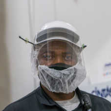 A masked Hearthside worker wearing a face mask, mesh mask, and clear face shield