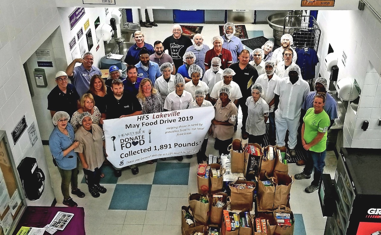 Lakeville employees hold a large banner for a food drive.