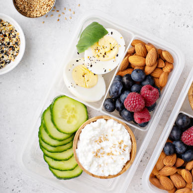 A refrigerated tray, packed to the brim with eggs, fruit, nuts, and cucumbers