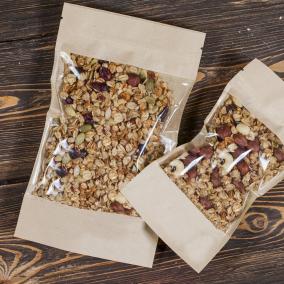 Two side-seal pouches filled with healthy nuts and fruits, on a dark wooden backdrop