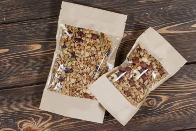 Two side-seal pouches filled with healthy nuts and fruits, on a dark wooden backdrop