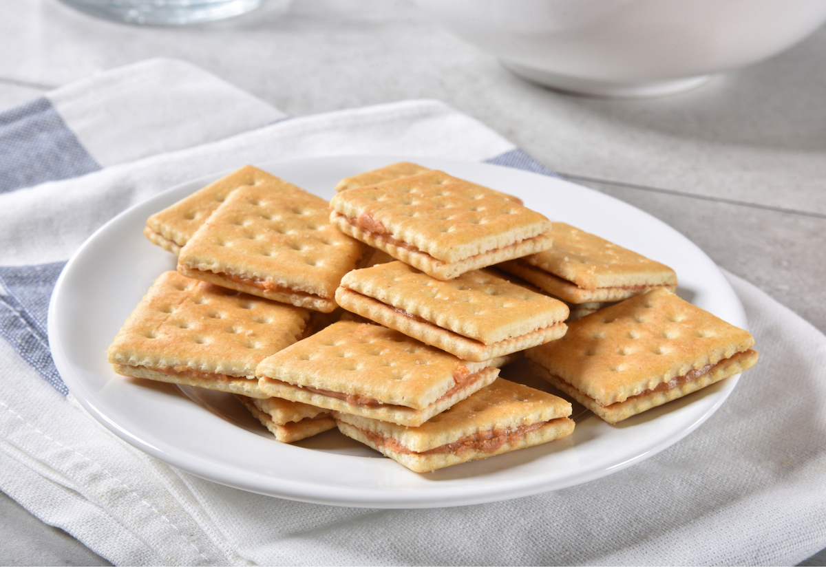 A stack of crackers with condiments sandwiched in the middle, on a white plate