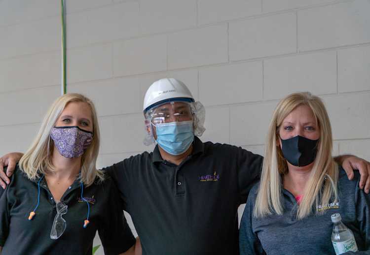 Three masked Hearthside workers stand side-by-side against a white wall.