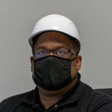 A masked Hearthside worker wearing a white helmet and black mask