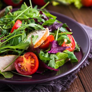 A fresh green salad, loaded with chicken, tomatoes and mixed greens