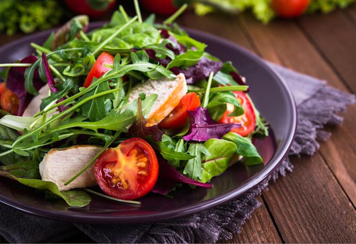 A fresh green salad, loaded with chicken, tomatoes and mixed greens