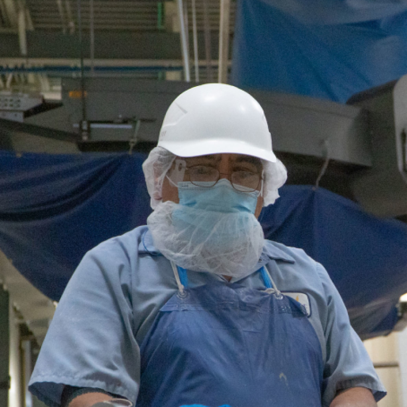 A masked Hearthside worker wearing a white hat
