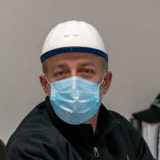 A masked Hearthside worker with a blue mask and white helmet