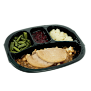 A frozen turkey dinner, with beans, turkey, gravy, potatoes and cranberry sauce