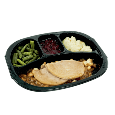 A frozen turkey dinner, with beans, turkey, gravy, potatoes and cranberry sauce