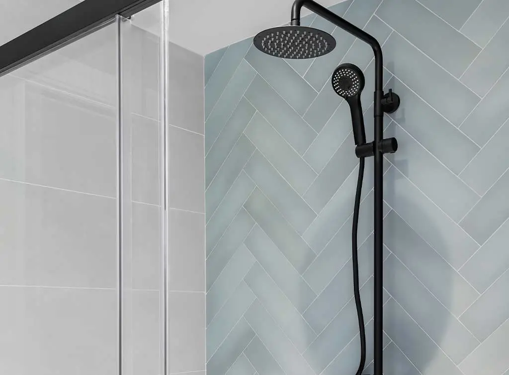 black shower unit against herringbone tiles