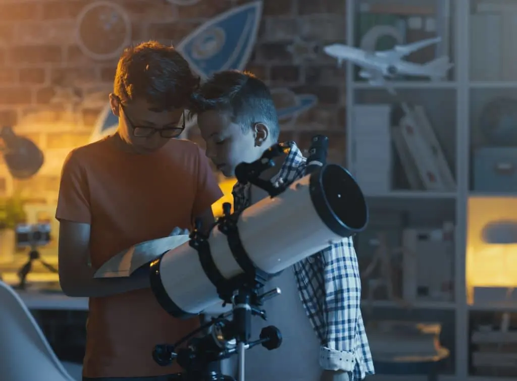 Children playing with a large telescope to stargaze