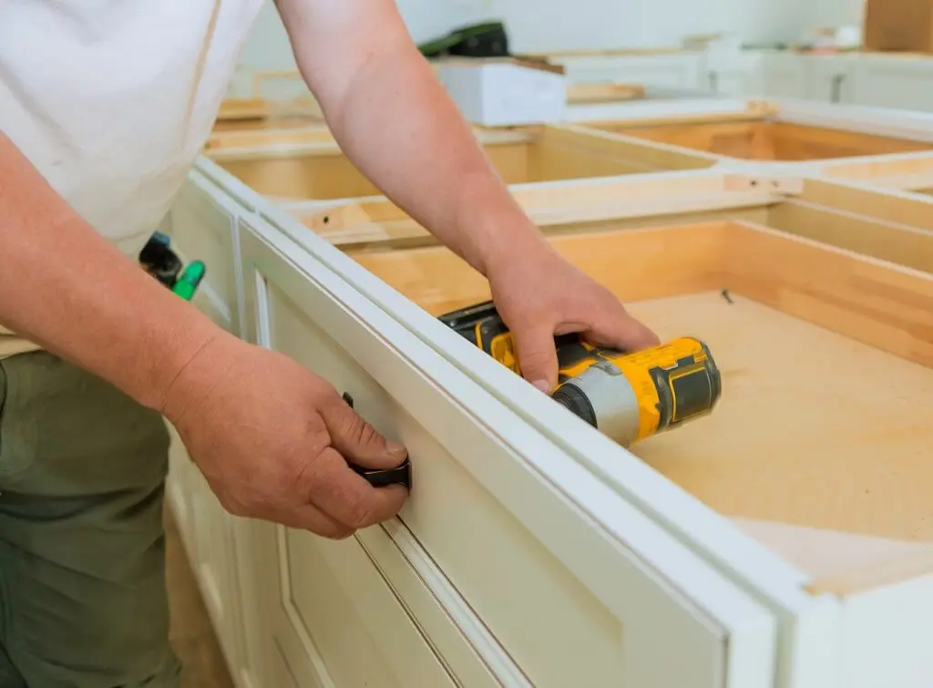 https://www.checkatrade.com/blog/wp-content/uploads/2024/12/fitting-handle-to-kitchen-drawers-during-installation.jpeg