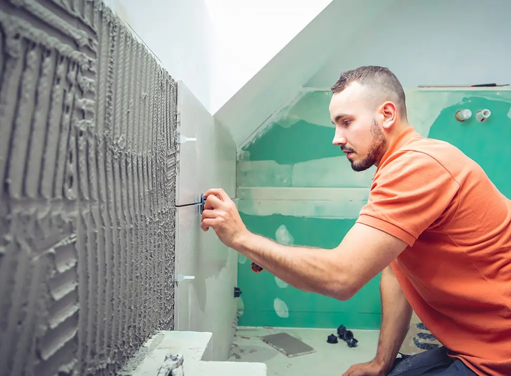 Tiler installing wall tiles in a bathroom