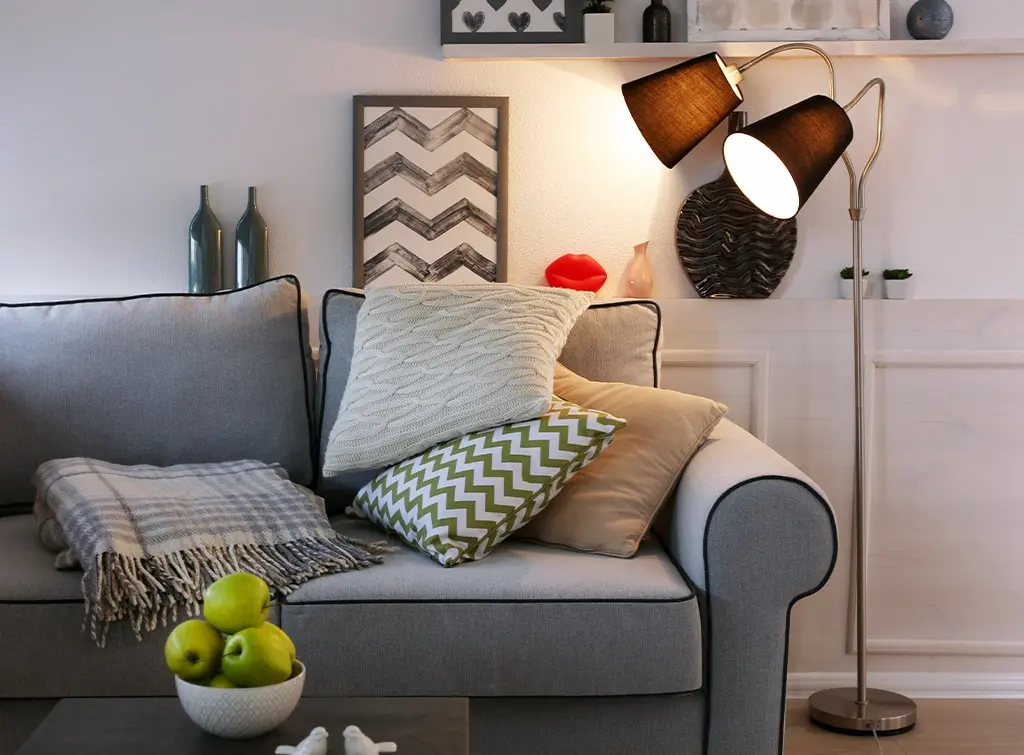Cottage furniture ideas. Rustic floor lamp overlooking a cosy grey couch.