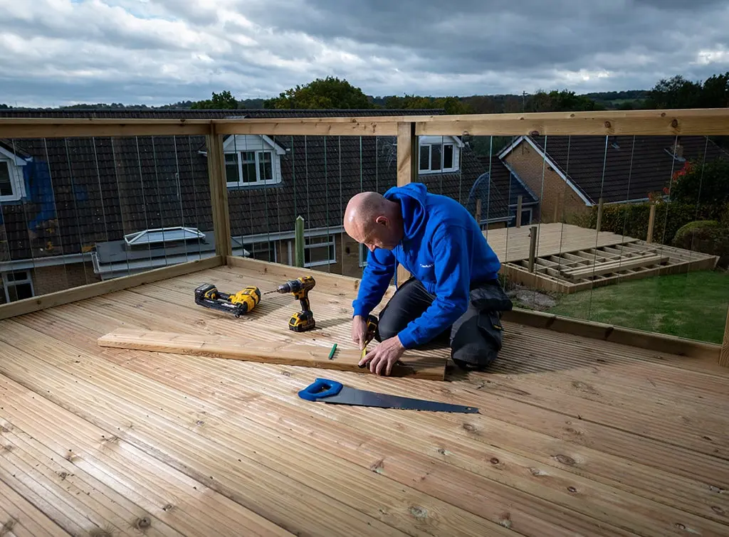 https://www.checkatrade.com/blog/wp-content/uploads/2024/08/decking-carpenter-being-physically-active-at-work.jpg