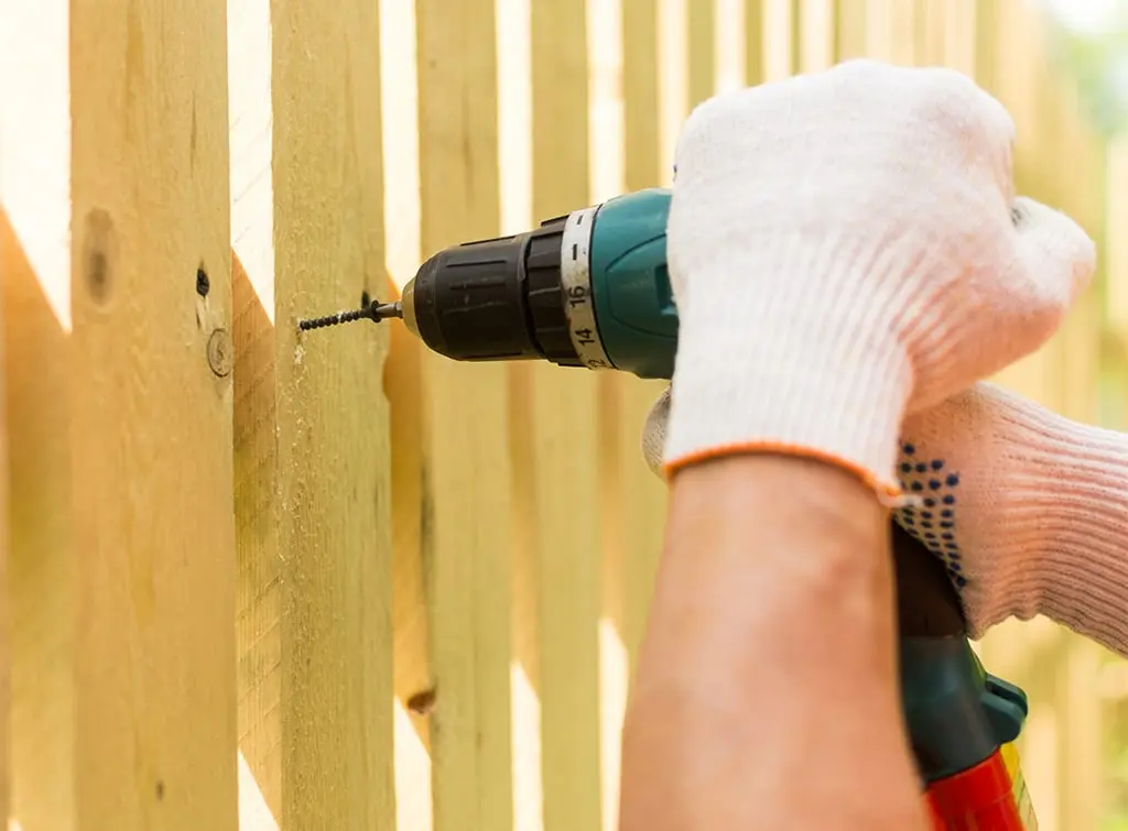 Fencing installer drilling screws into a fence panel